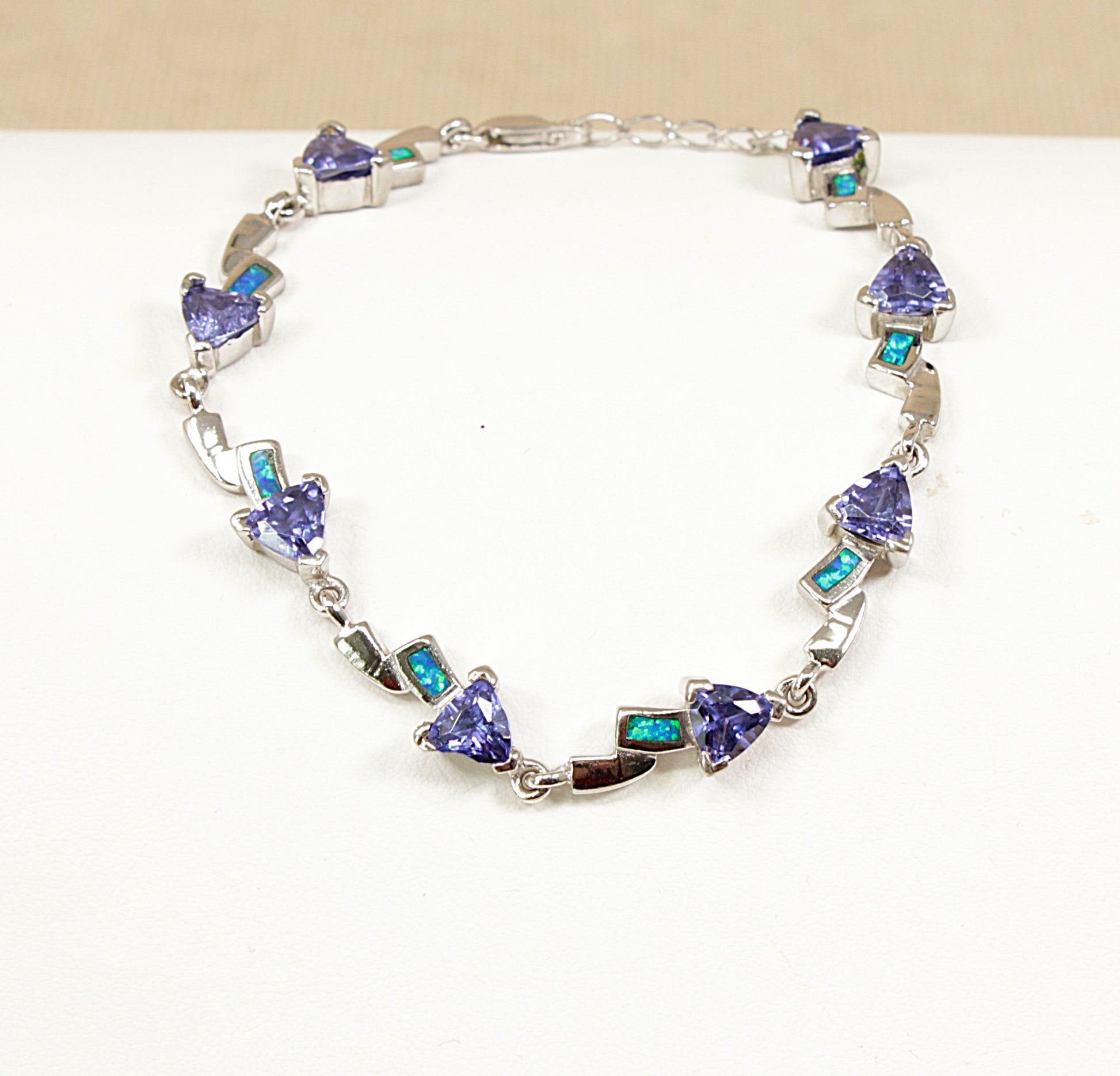 Silver bracelet with opal and heart-shaped blue gemstones on a white background