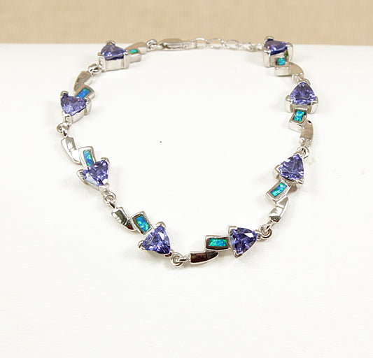 Silver bracelet with opal and heart-shaped blue gemstones on a white background