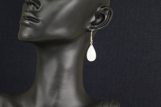 Teardrop-shaped earring on a black mannequin against a dark background