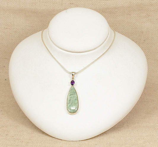 Necklace with a green pendant on a white mannequin bust against a beige background