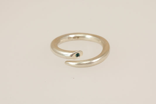 Silver ring with a small blue diamond gemstone on a beige background