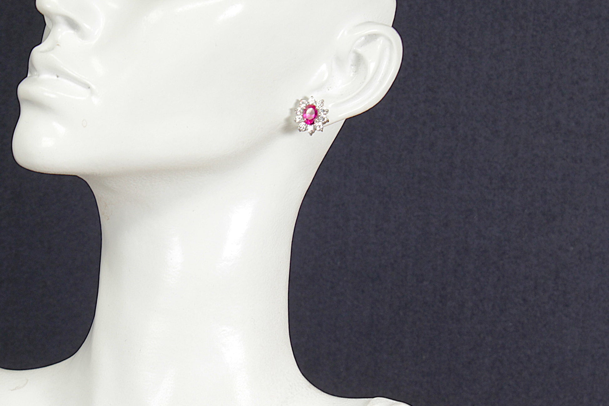 Ruby earring on a mannequin ear with a dark background