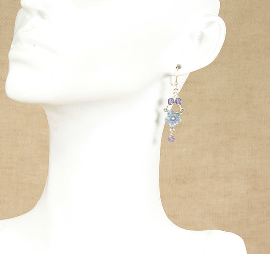 Earring displayed on a mannequin ear with a plain background