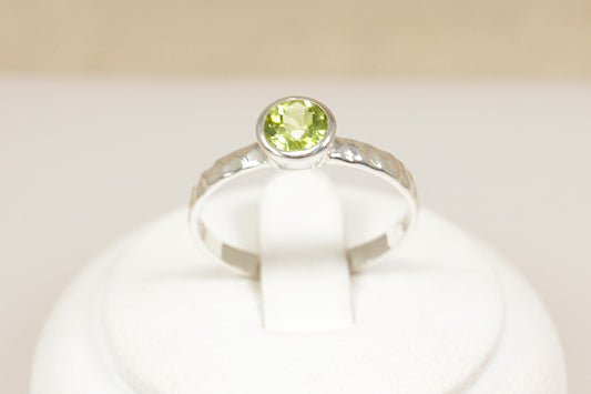 Silver ring with a green gemstone on a white background