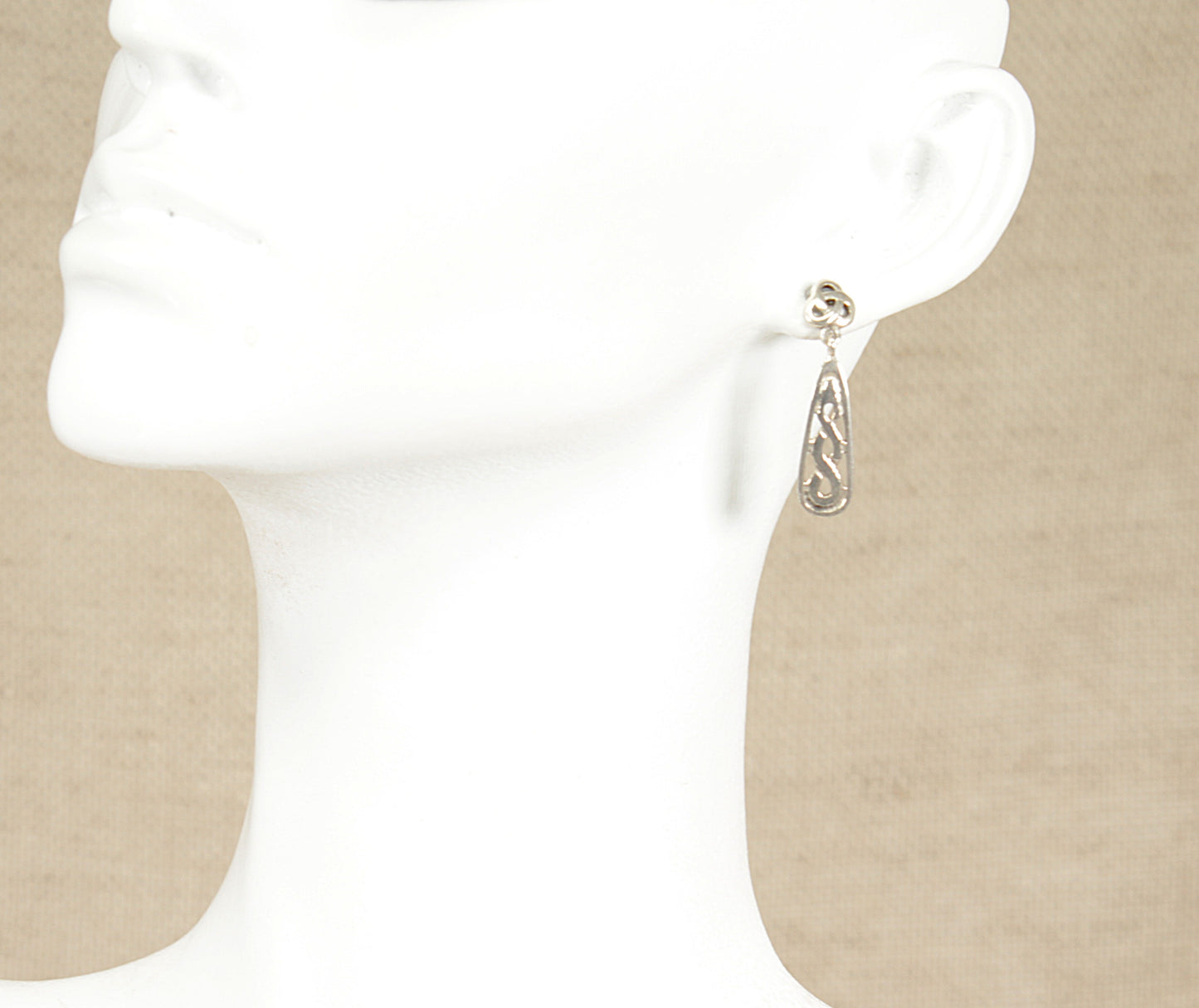 Silver earring on a beige background