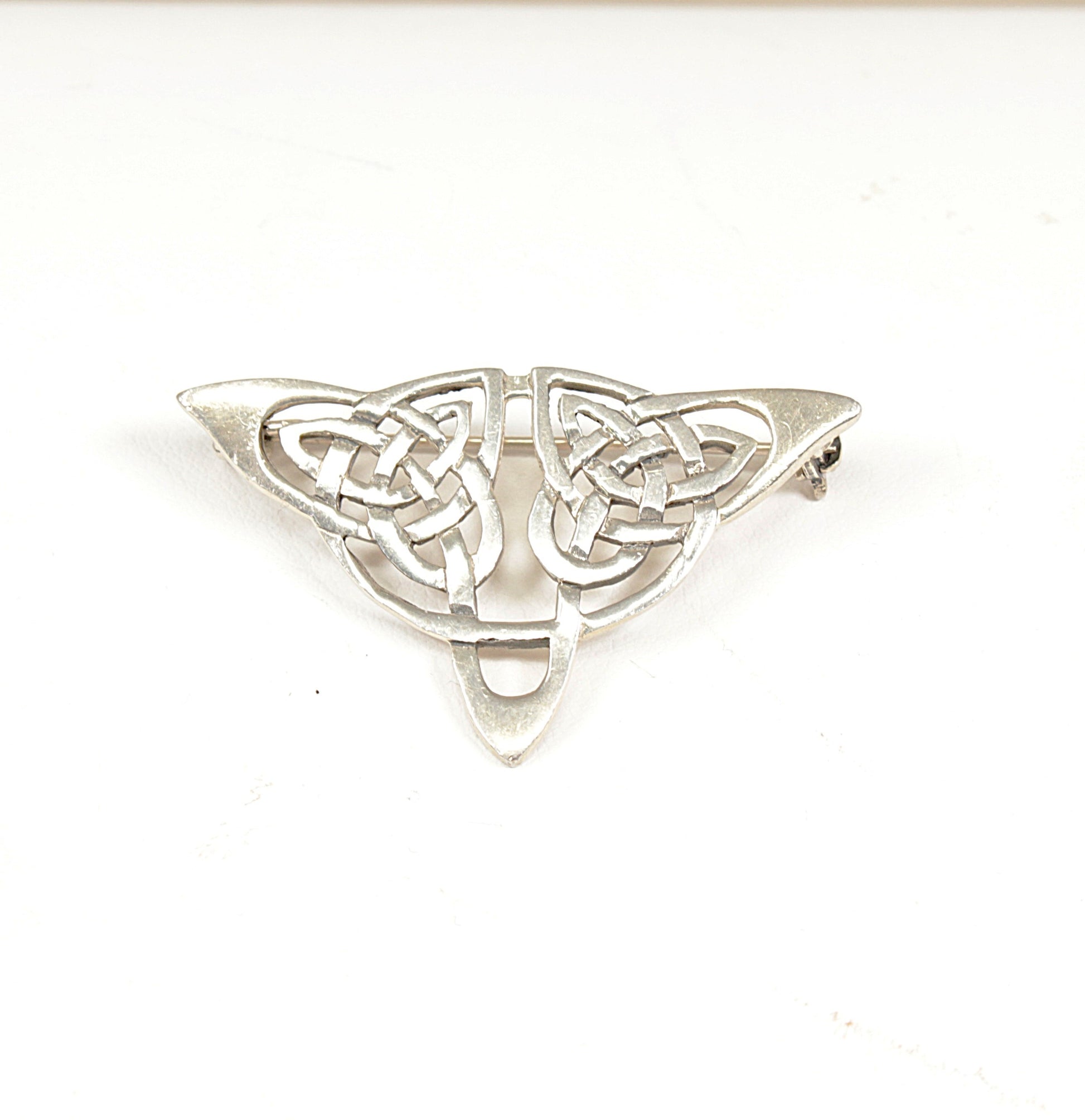 Silver Celtic knot brooch on a white background