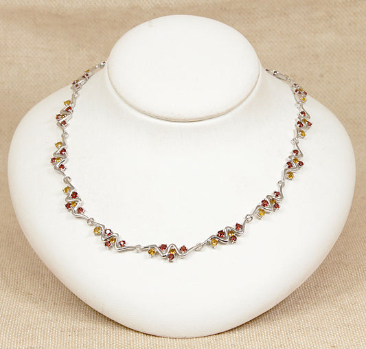 Silver necklace with multi gemstones citrine garnet on a white stand against a beige background
