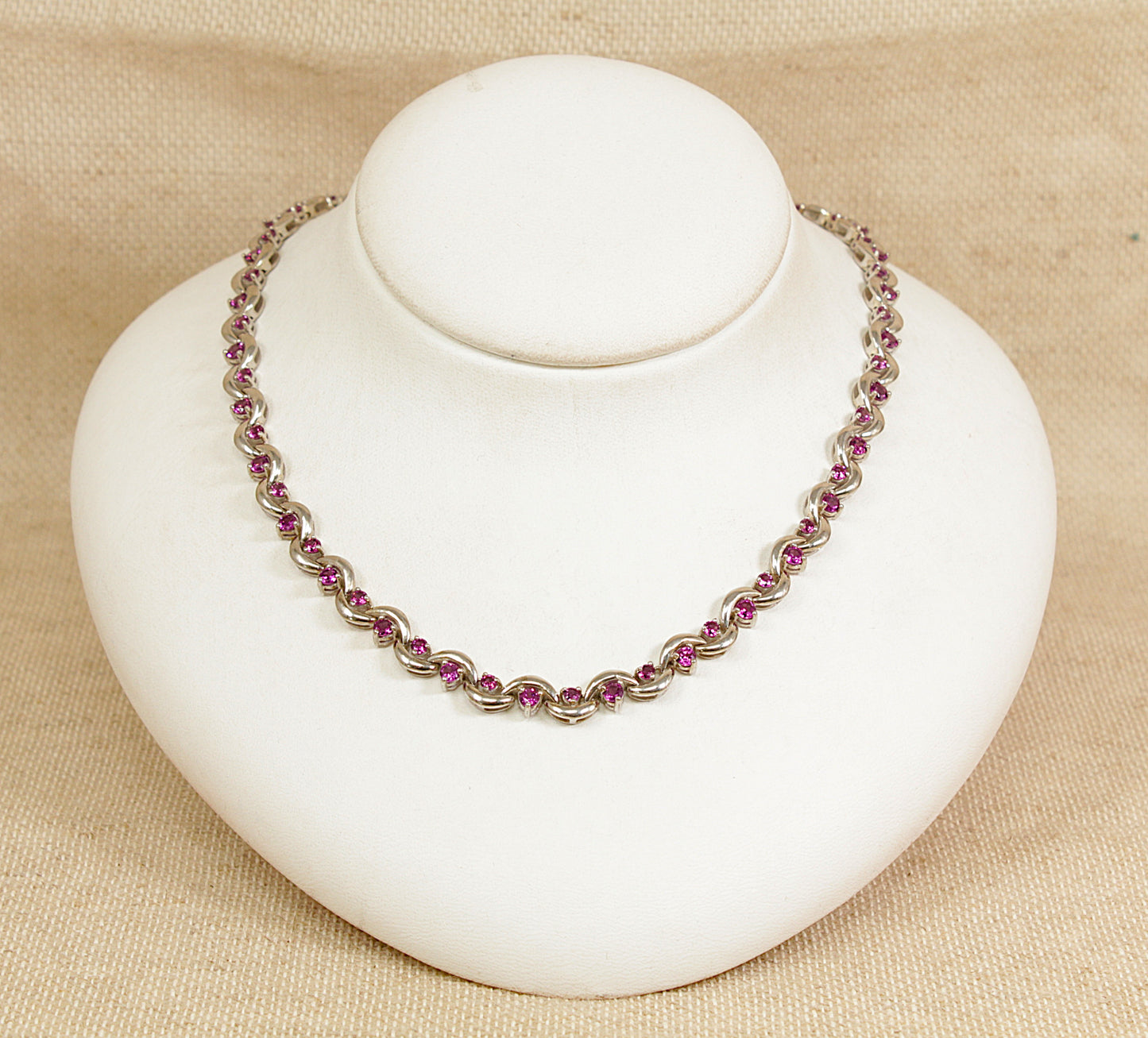 Necklace with pink and purple beads on a white mannequin bust against a beige background