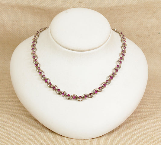 Necklace with pink and purple beads on a white mannequin bust against a beige background