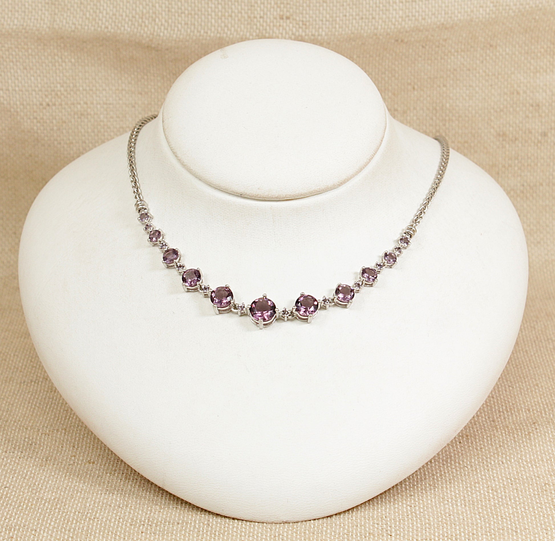 Necklace with purple amethyst colour  gemstones on a white mannequin bust against a beige background