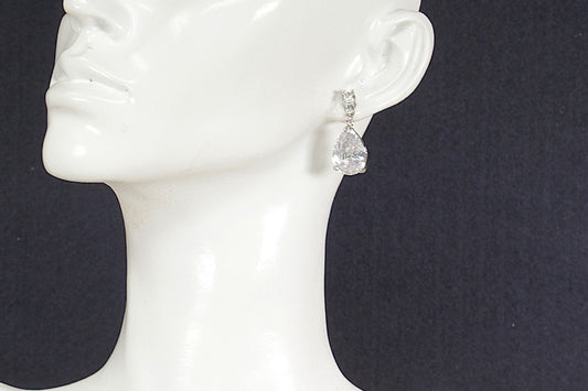 Silver teardrop earrings on a white mannequin ear against a black background