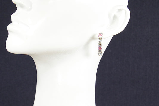 Earrings on a mannequin ear against a dark background