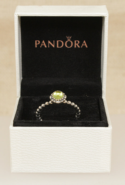 Pandora solitaire ring with a green peridot gemstone in a Pandora box on a beige background