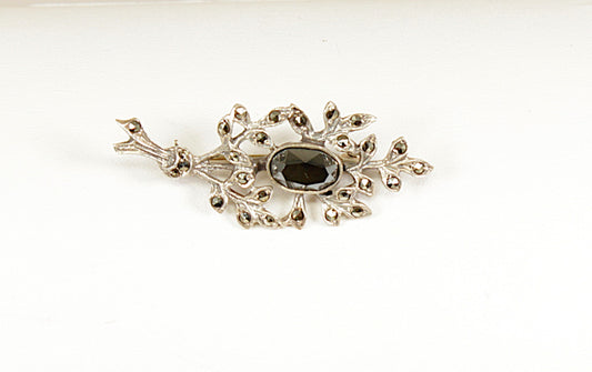 Decorative brooch with central gemstone on a white background