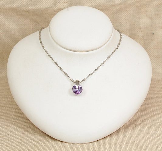 Necklace with a purple round-shaped pendant on a white bust against a beige background