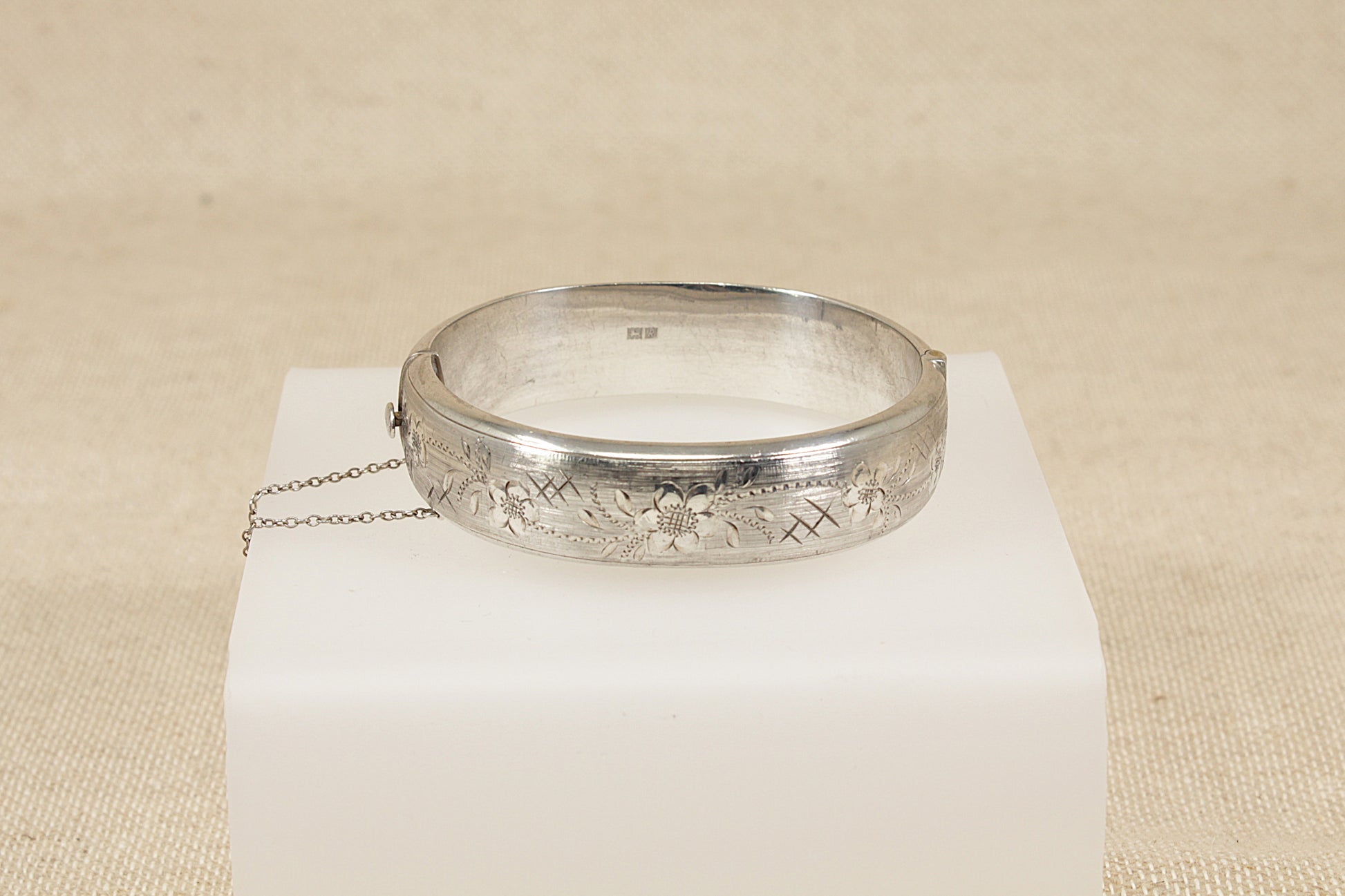 Vintage Antique Silver bracelet bangle  on a white cube with a beige background