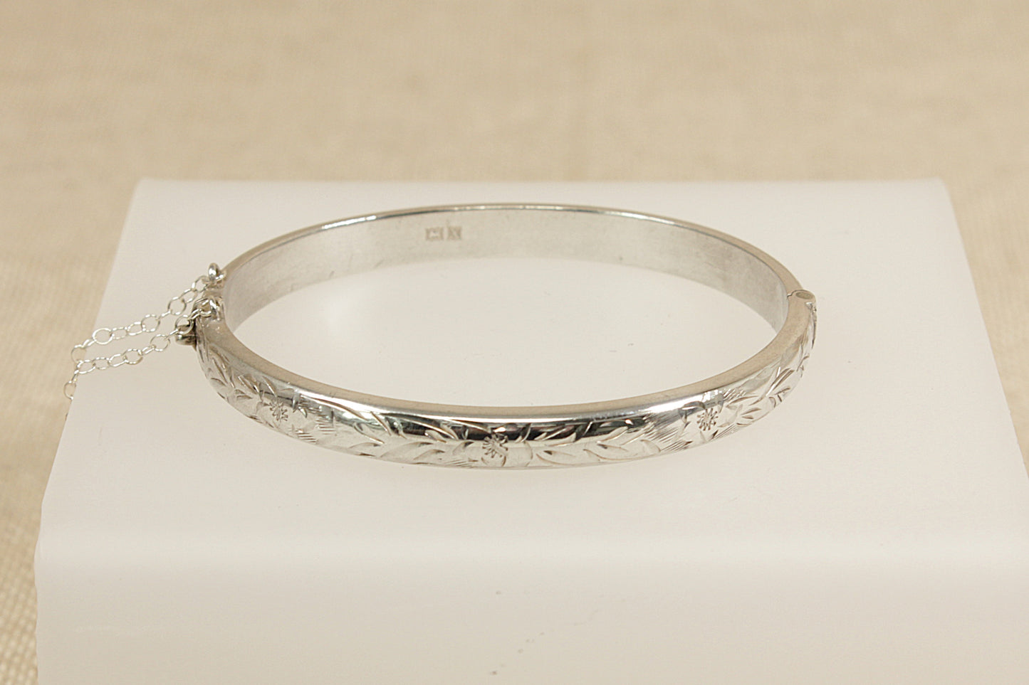 Silver bracelet on a white cushion with a beige background