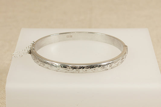Silver bracelet on a white cushion with a beige background