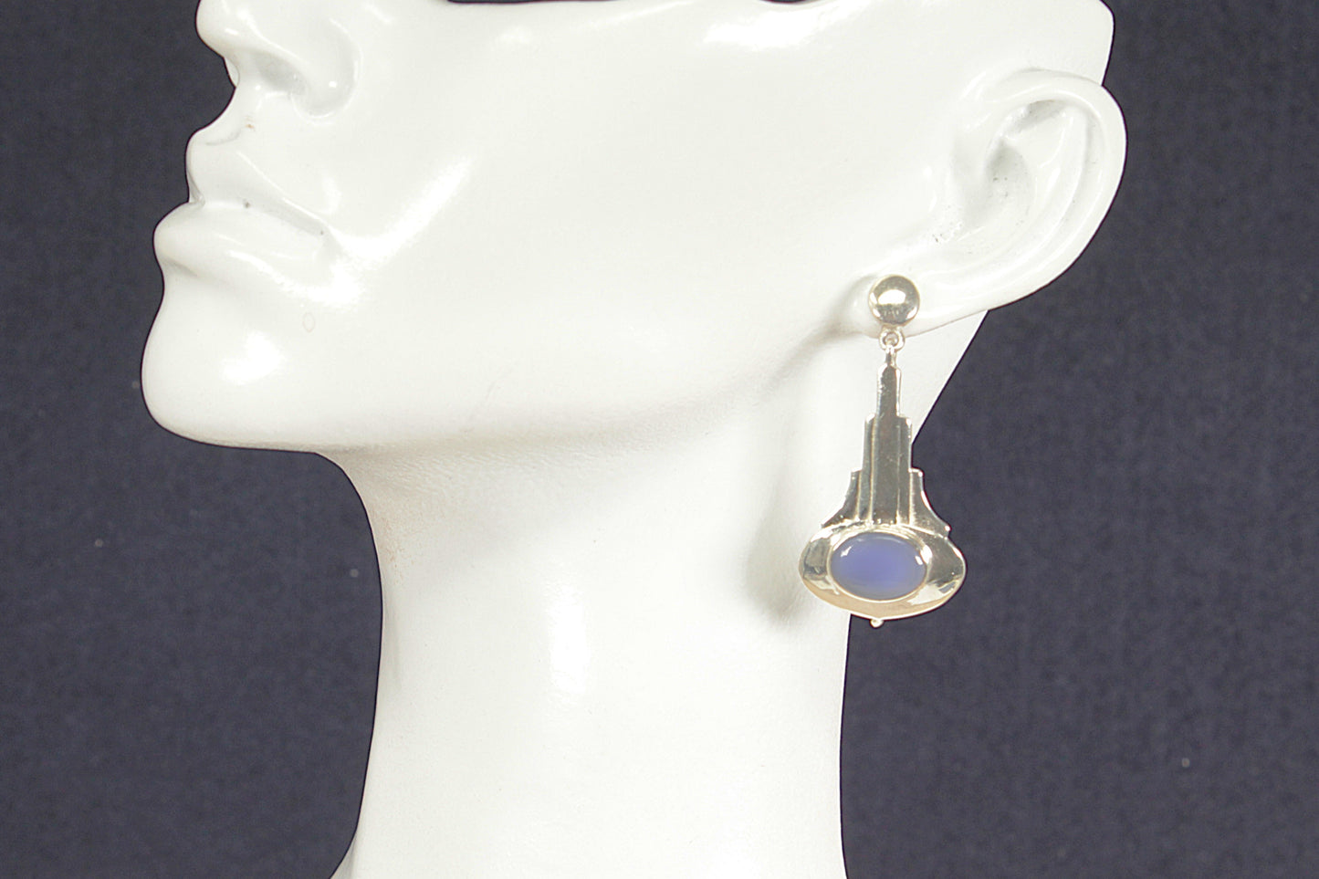 Art Deco earring with blue chalcedony gemstone on a mannequin ear against a dark background