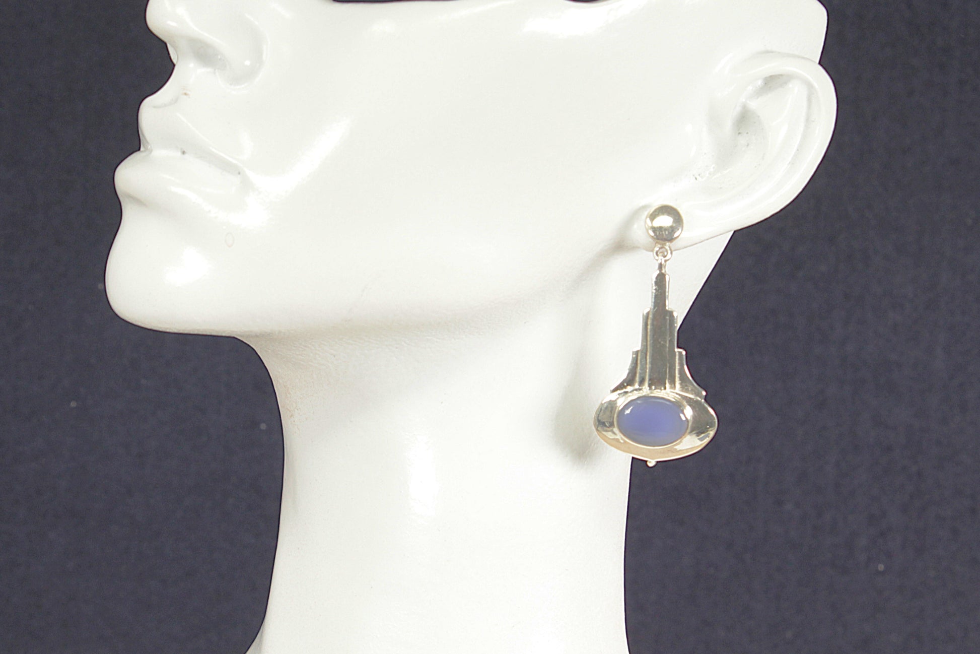 Art Deco earring with blue chalcedony gemstone on a mannequin ear against a dark background