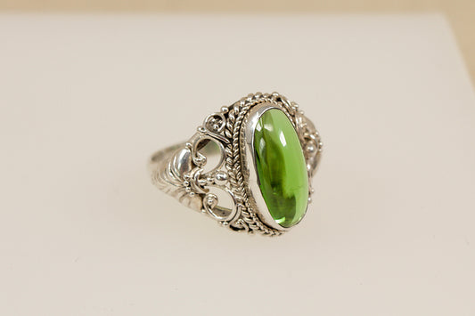 Silver statement ring with a green gemstone on a beige background
