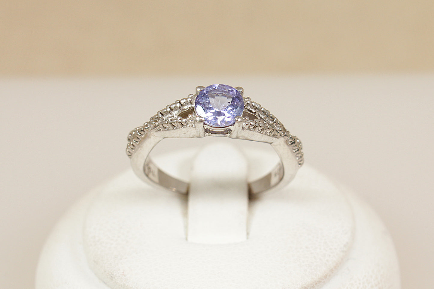 Silver solitaire ring with a blue iolite gemstone on a white cushion