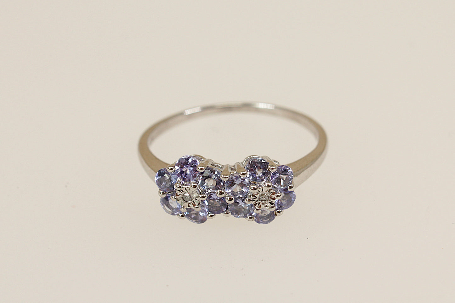 Silver ring with blue iolite and diamond   gemstones on a beige background