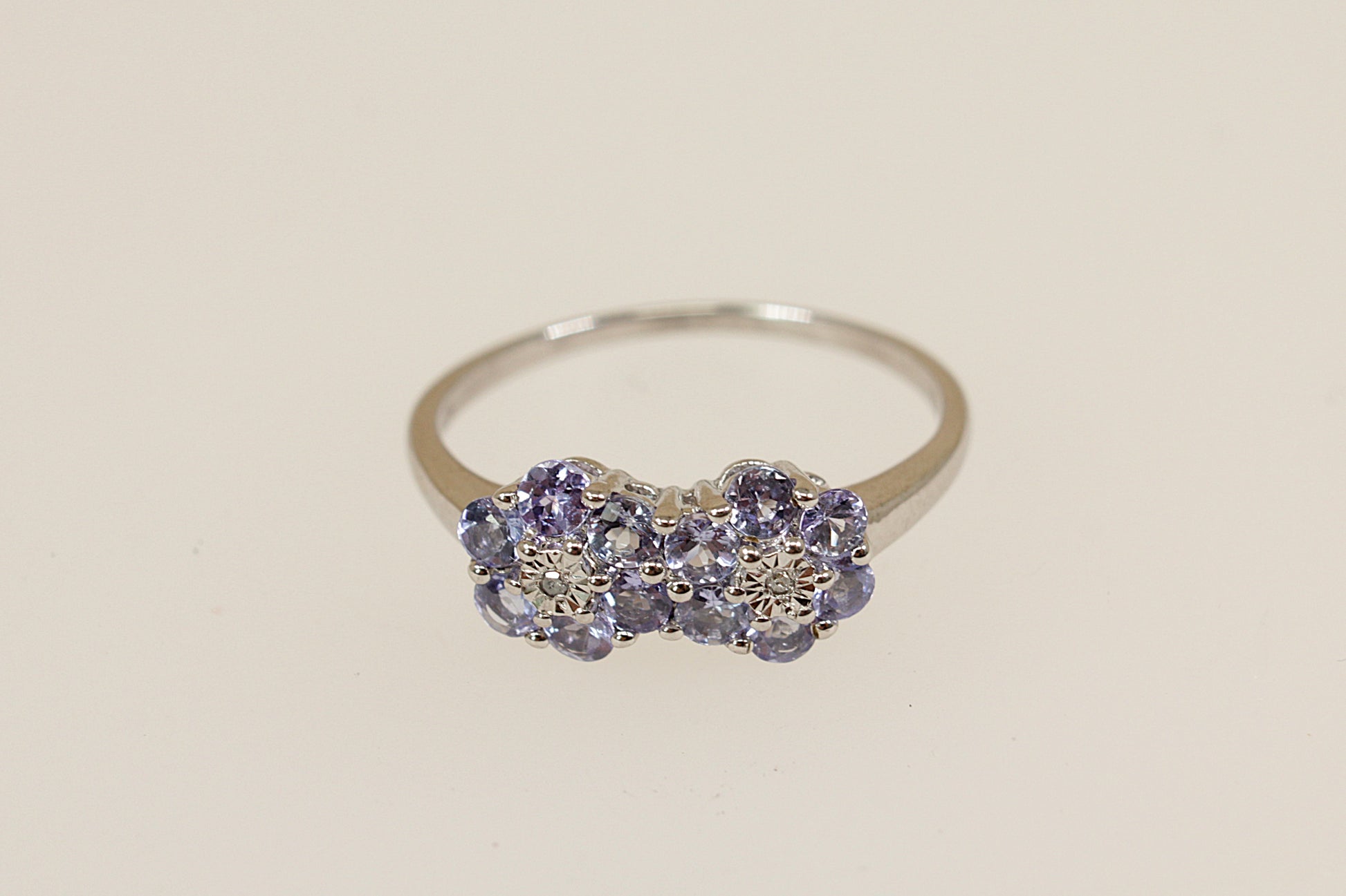 Silver ring with blue iolite and diamond   gemstones on a beige background
