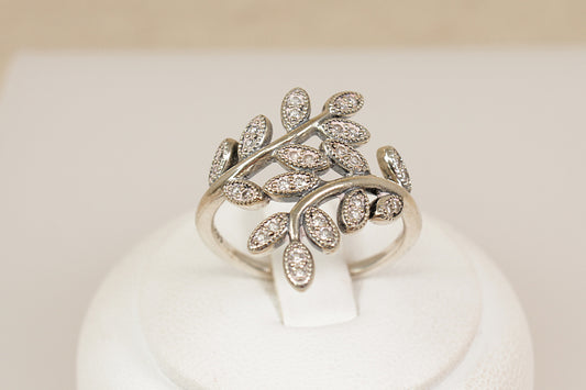 Silver leaf-shaped ring with embedded stones on a white stand