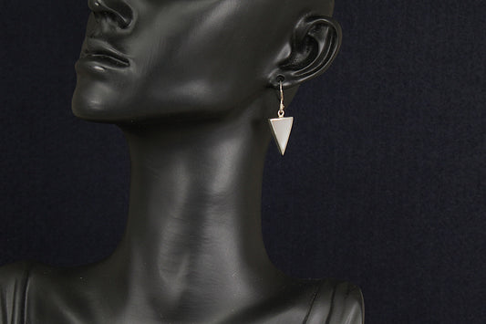 Mannequin wearing silver mother of pearl triangle earrings against a dark background
