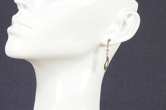 Gold and crystal earrings on a white mannequin head against a dark background