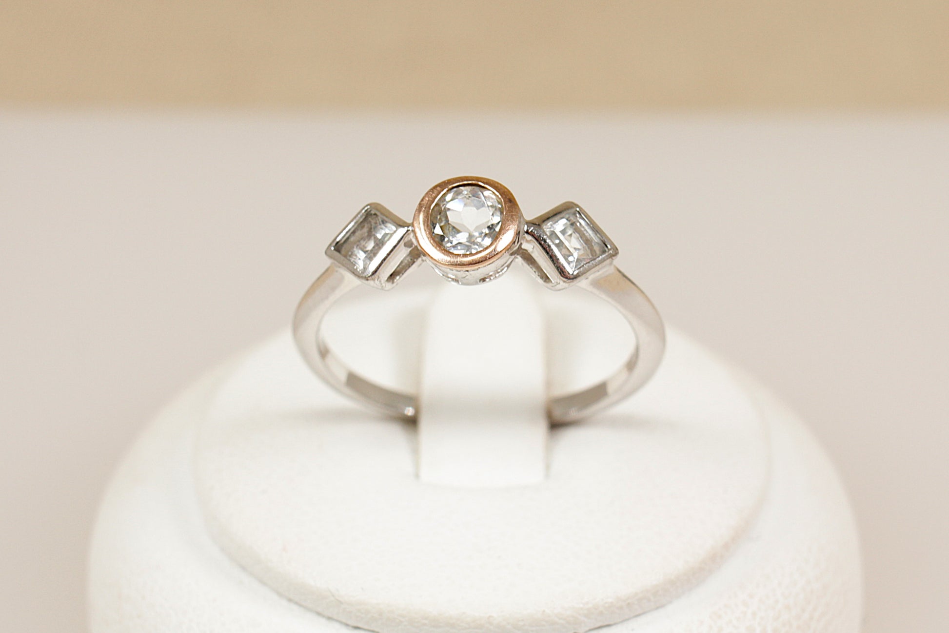 Clogau trilogy ring on a white stand with a beige background