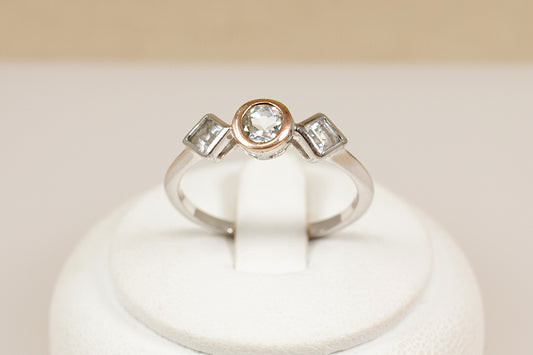Clogau trilogy ring on a white stand with a beige background