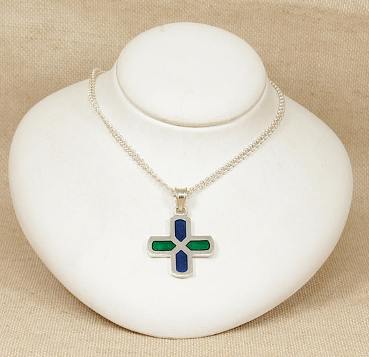 Silver necklace with a cross pendant on a white stand against a beige background