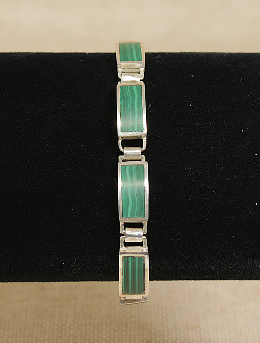 Silver bracelet with green malachite stones on a black stand