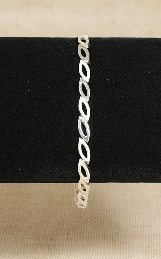 Silver bracelet on a black stand with a beige background