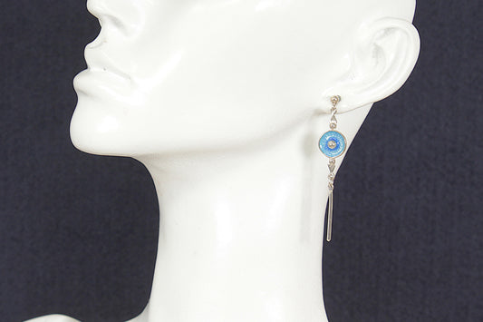 Earring with blue gemstone on a mannequin ear against a dark background