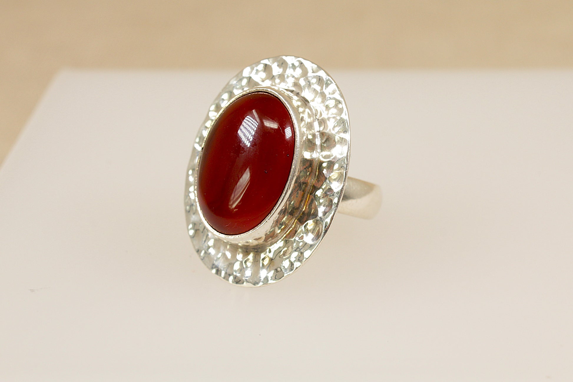 Silver ring with a red stone on a beige background