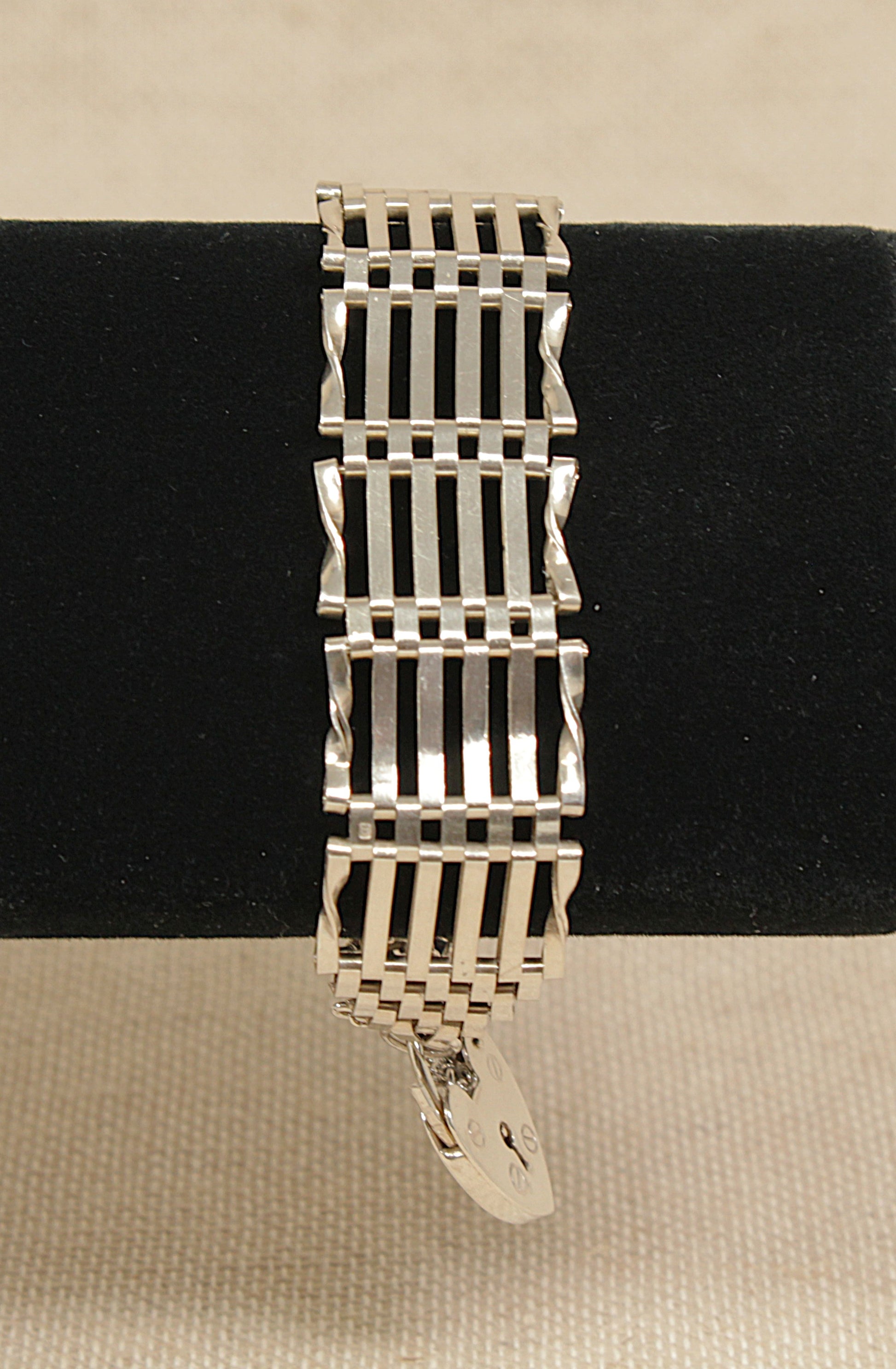 Classic vintage silver gate bracelet on a black velvet cushion with a beige background