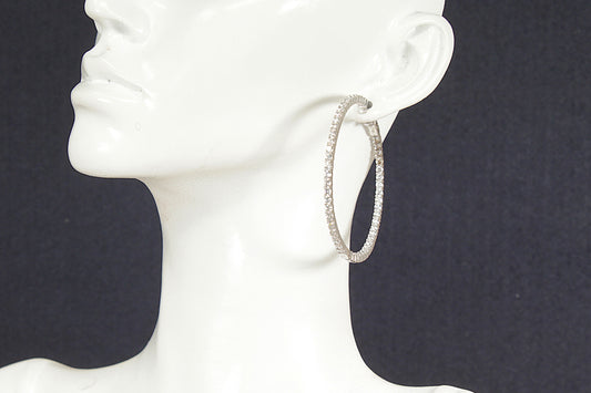 Silver hoop earrings on a white mannequin head against a black background