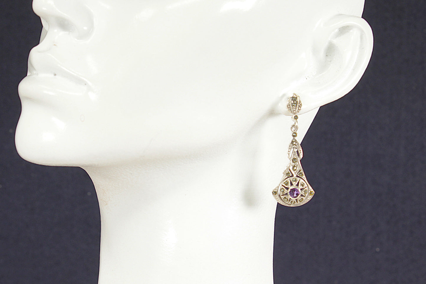 Silver Art Deco Amethyst Marcasite Earring on a mannequin ear with a dark background
