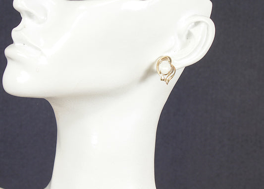 Gold opal stud earrings on a white mannequin head against a dark background