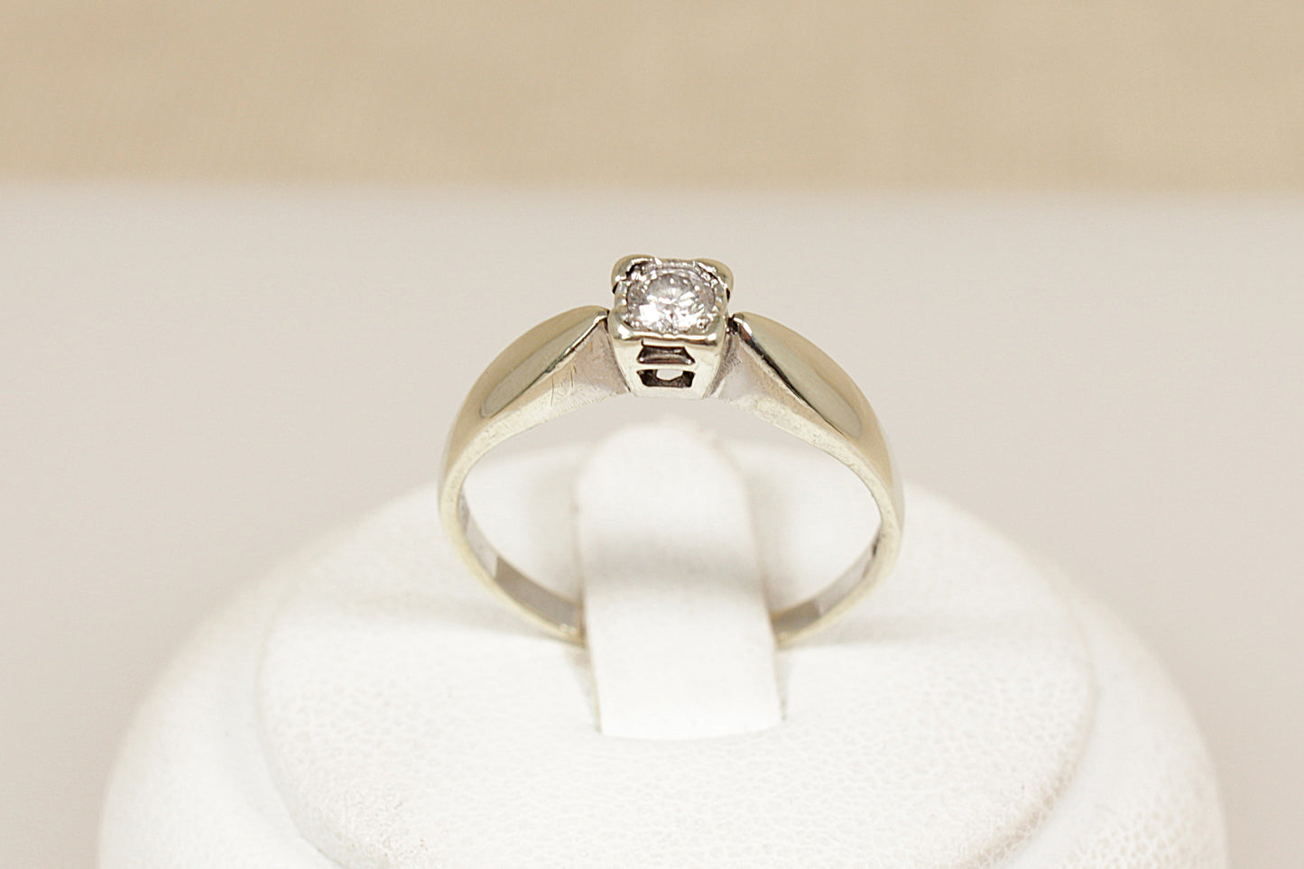 White gold diamond solitaire engagement ring on a white cushion