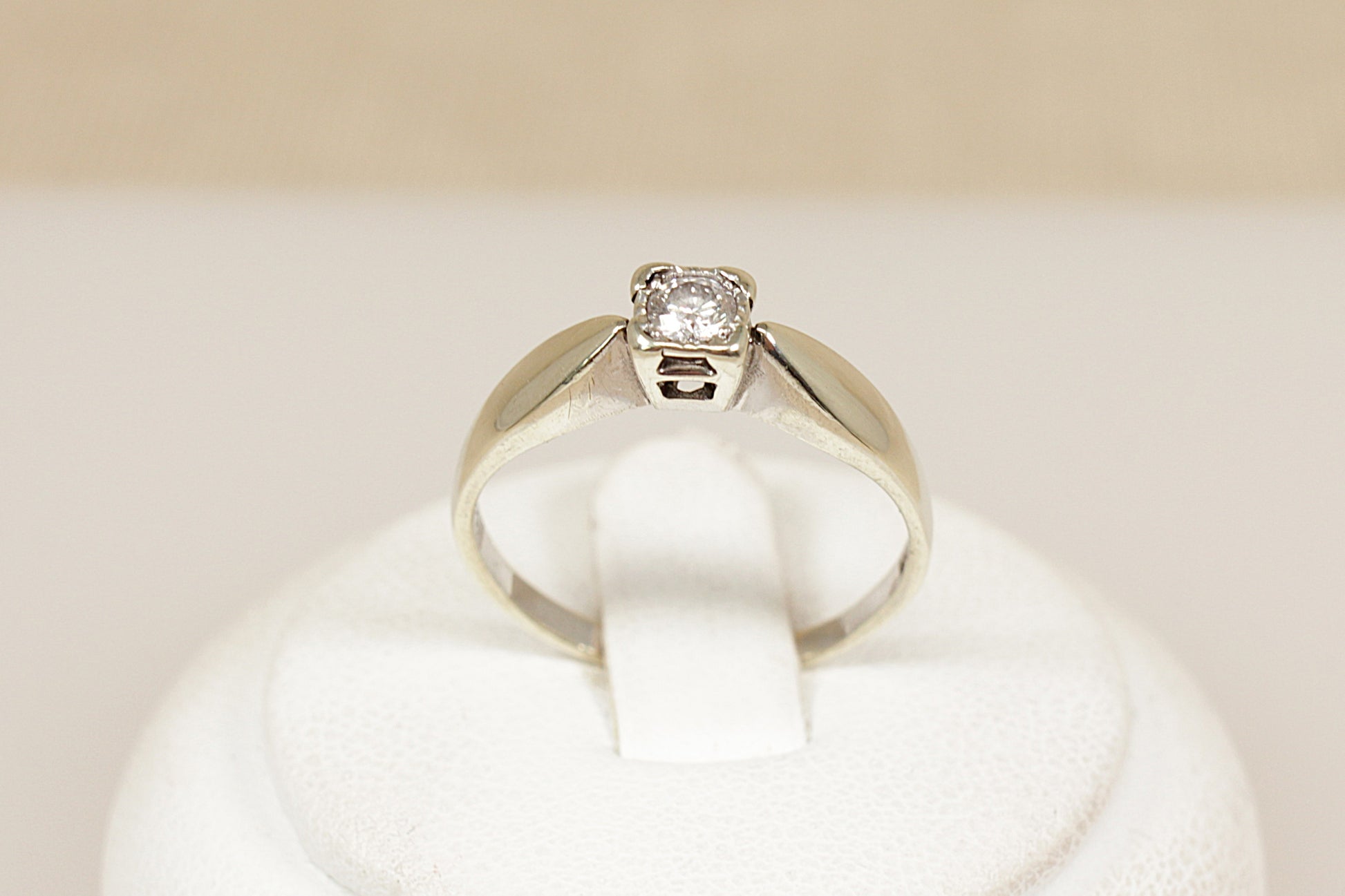 White gold diamond solitaire engagement ring on a white cushion