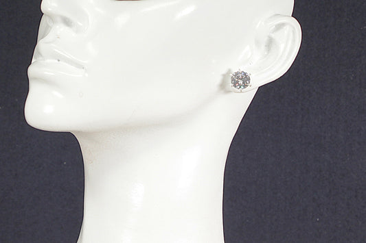 Silver earring on a mannequin ear against a dark background