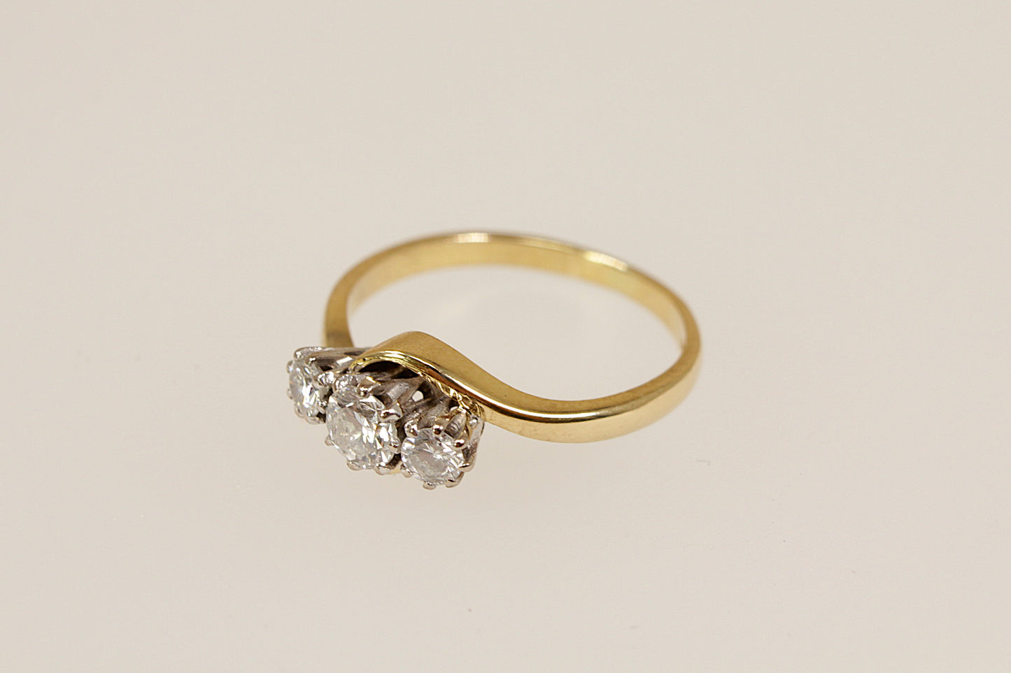 Gold ring with three diamonds on a beige background