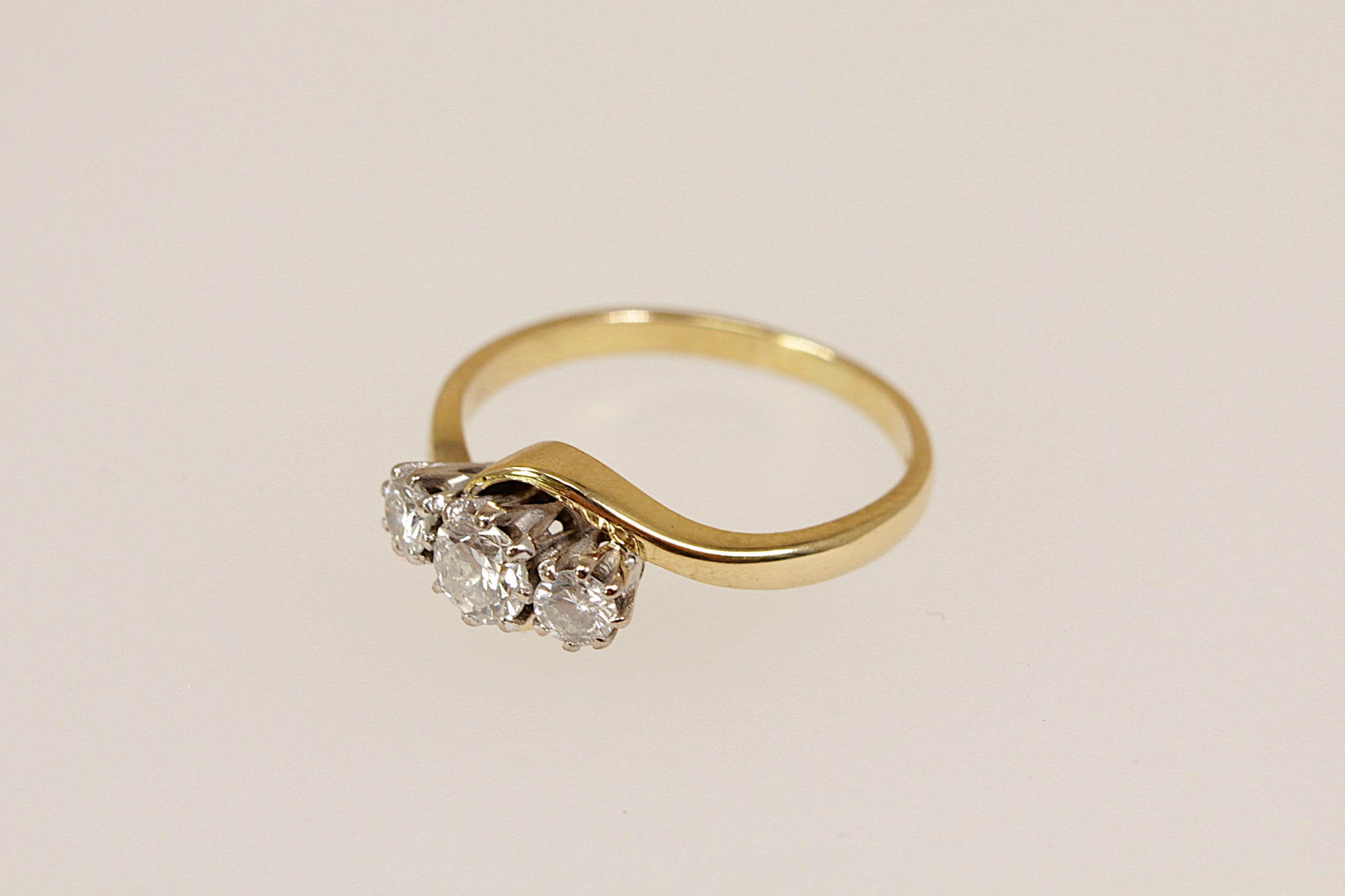 Gold ring with three diamonds on a beige background