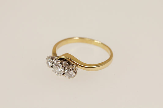 Gold ring with three diamonds on a beige background