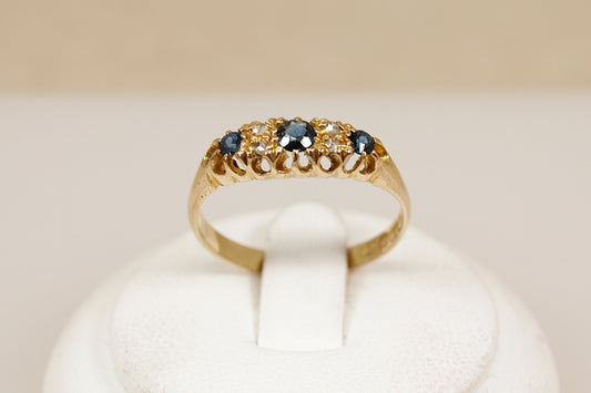 Antique 18ct sapphire and diamond  gold ring on a white cushion against a beige background