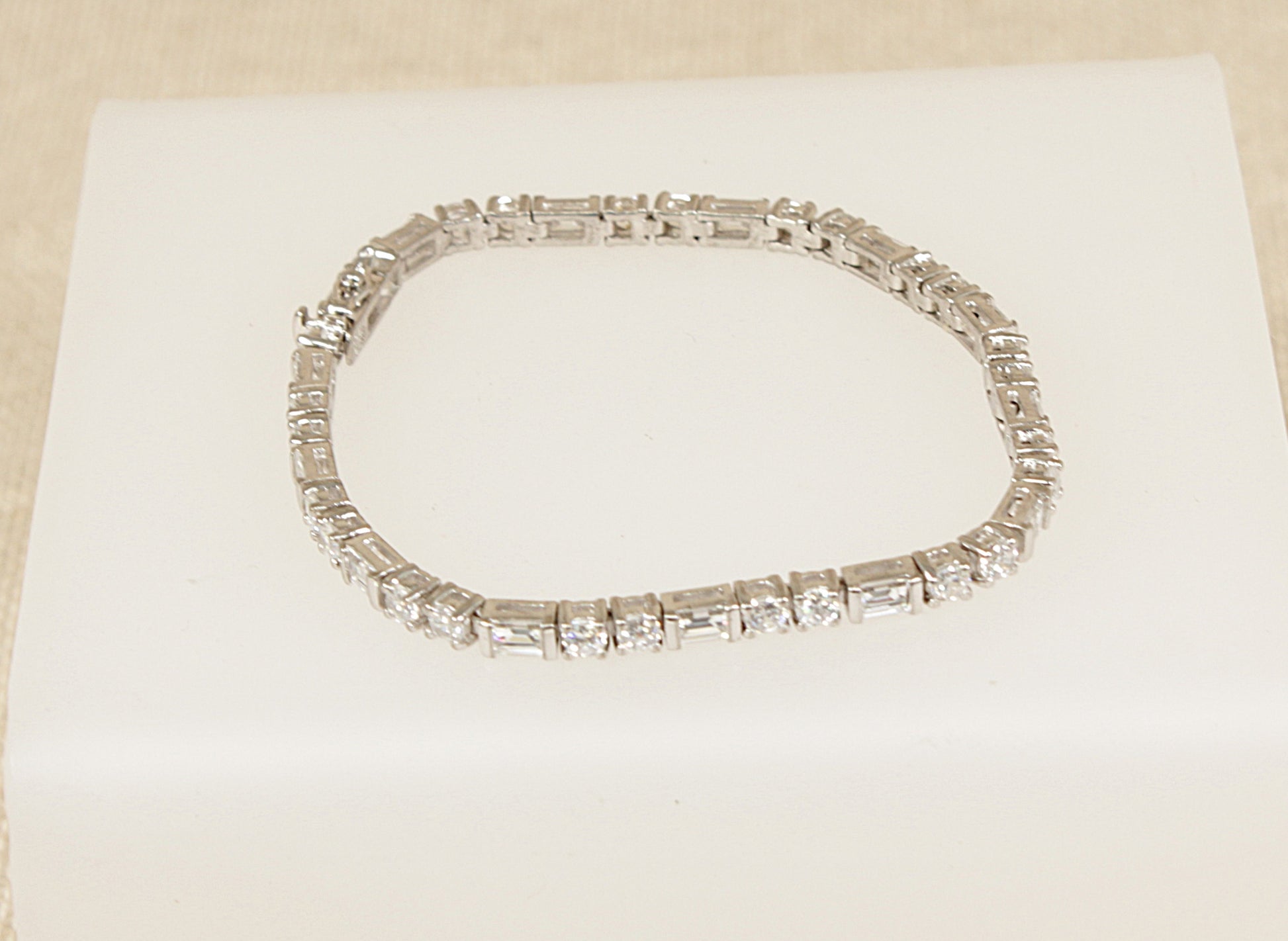 Silver bracelet with rectangular gemstones on a beige background